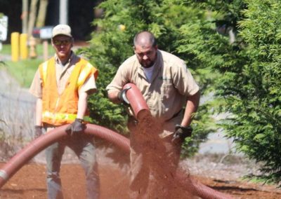 Bark King crew running blower hose across a landscaped bed
