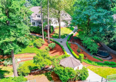 Aerial view of a large wooded residential property with freshly installed bark beds and winding paths